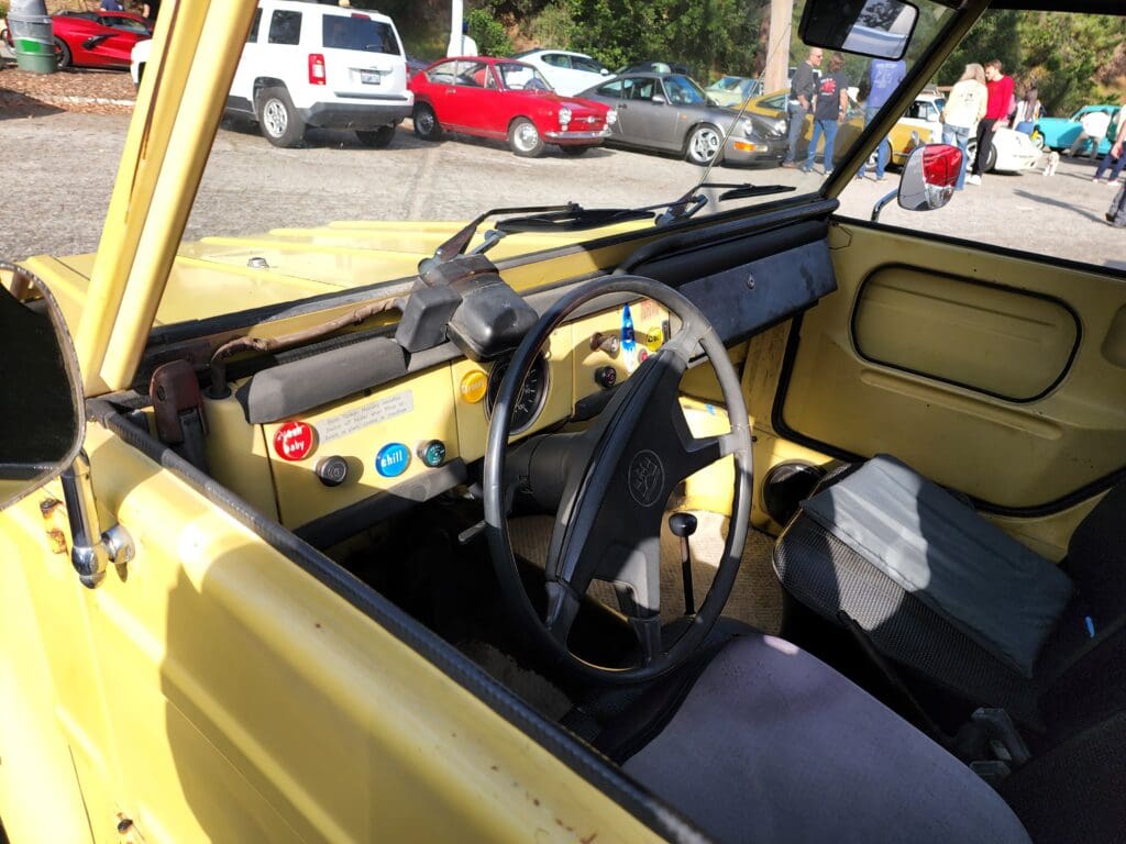 Interior of a vintage yellow car with a simple dashboard and steering wheel.