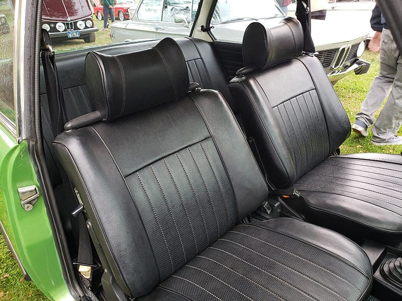 Vintage car interior with black leather seats and headrests.