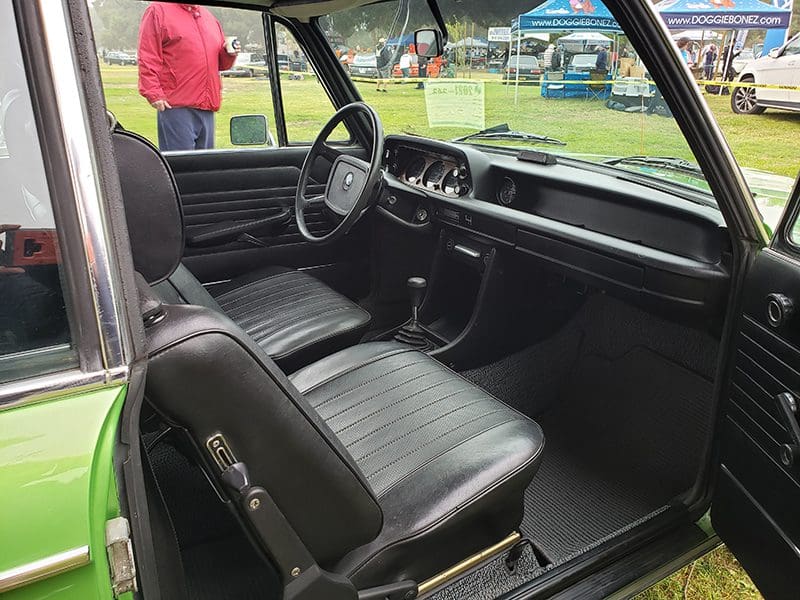 Interior of a vintage car with black seats and dashboard.