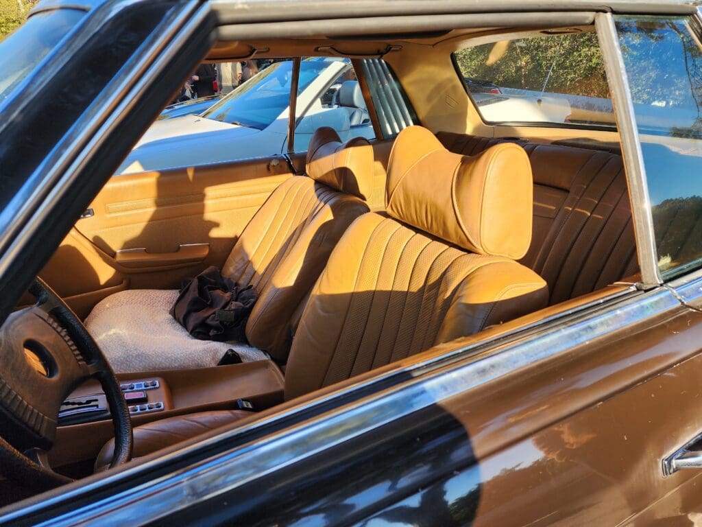 Vintage car interior with tan leather seats and classic design.