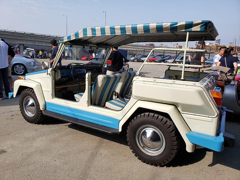 A vintage white and blue convertible SUV with no doors parked outdoors.