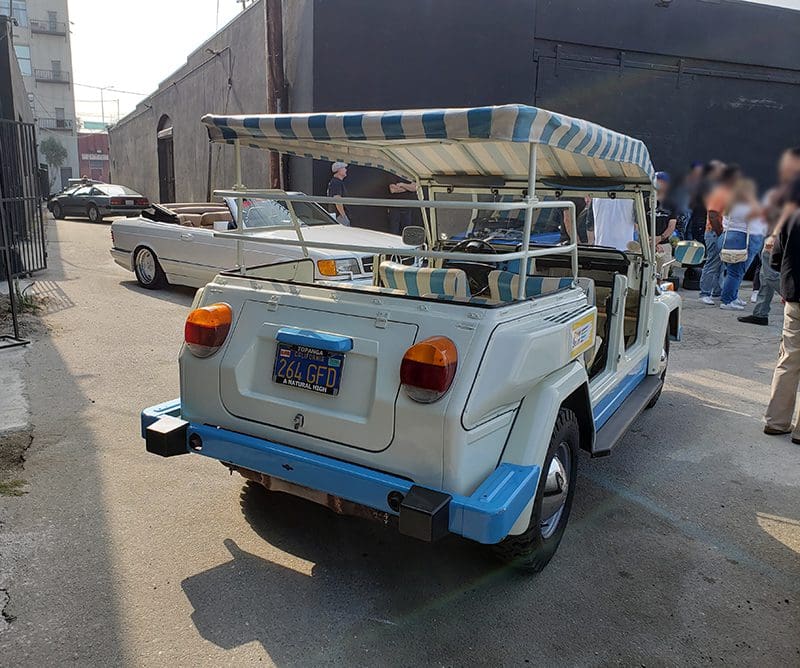 A vintage white jeep with a canopy parked outdoors.