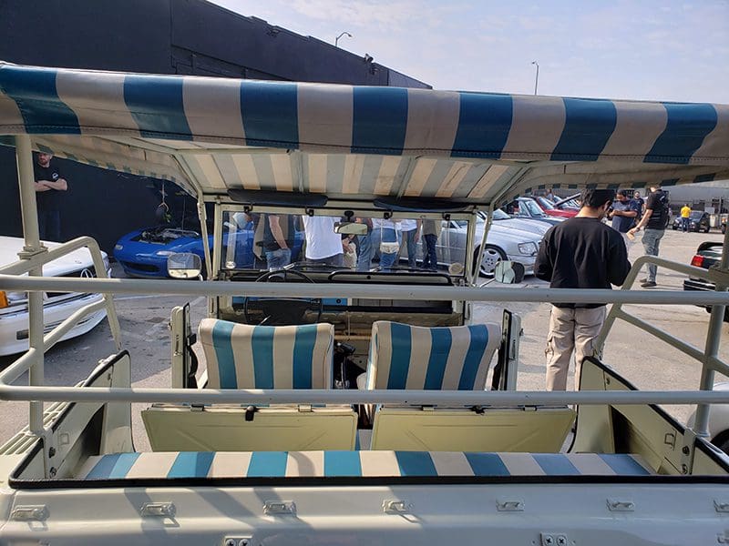 A striped canopy and seats on a boat with a waterfront view.