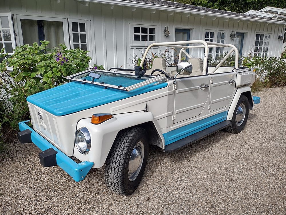 A vintage white and blue convertible car parked on a driveway.
