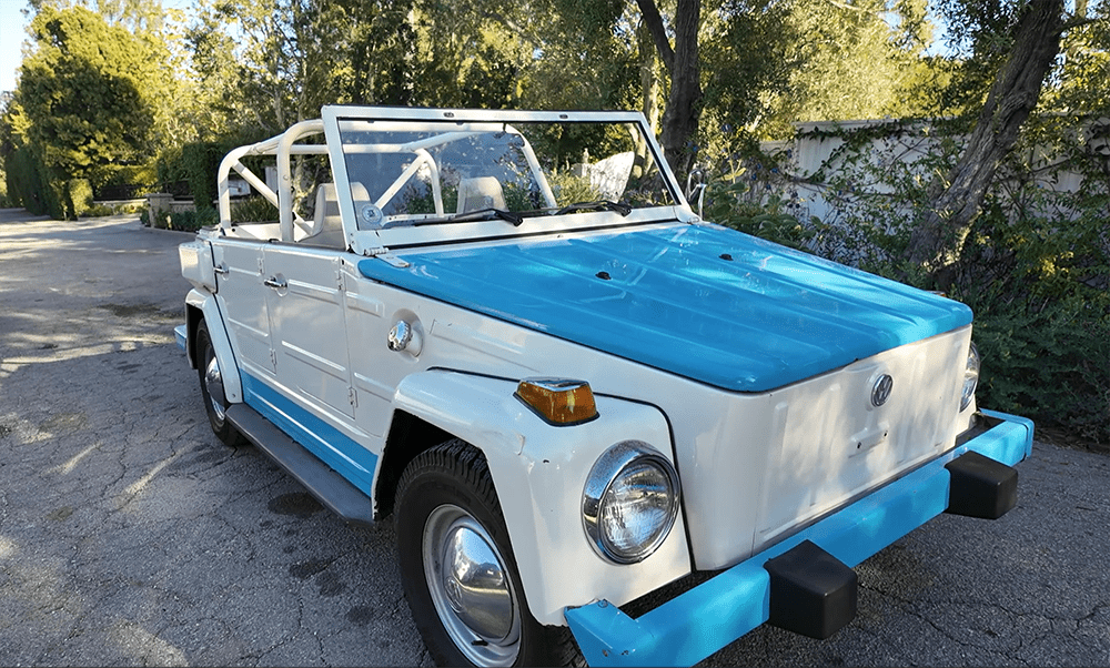 A vintage white and blue convertible car parked on a driveway.