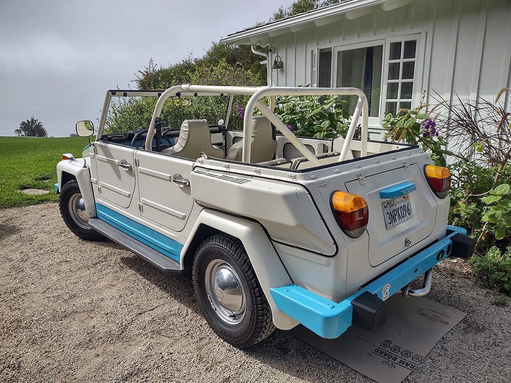 Vintage convertible car parked by a house with flower pots.
