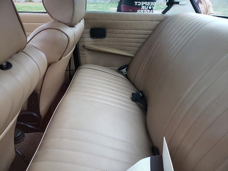 Beige leather car backseat with seatbelt.
