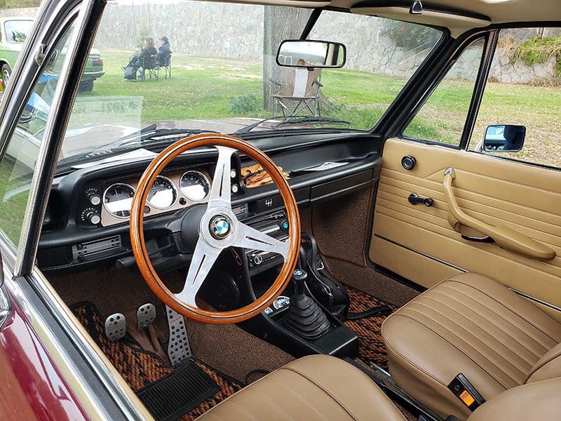 Vintage car interior with wooden steering wheel and classic dashboard.