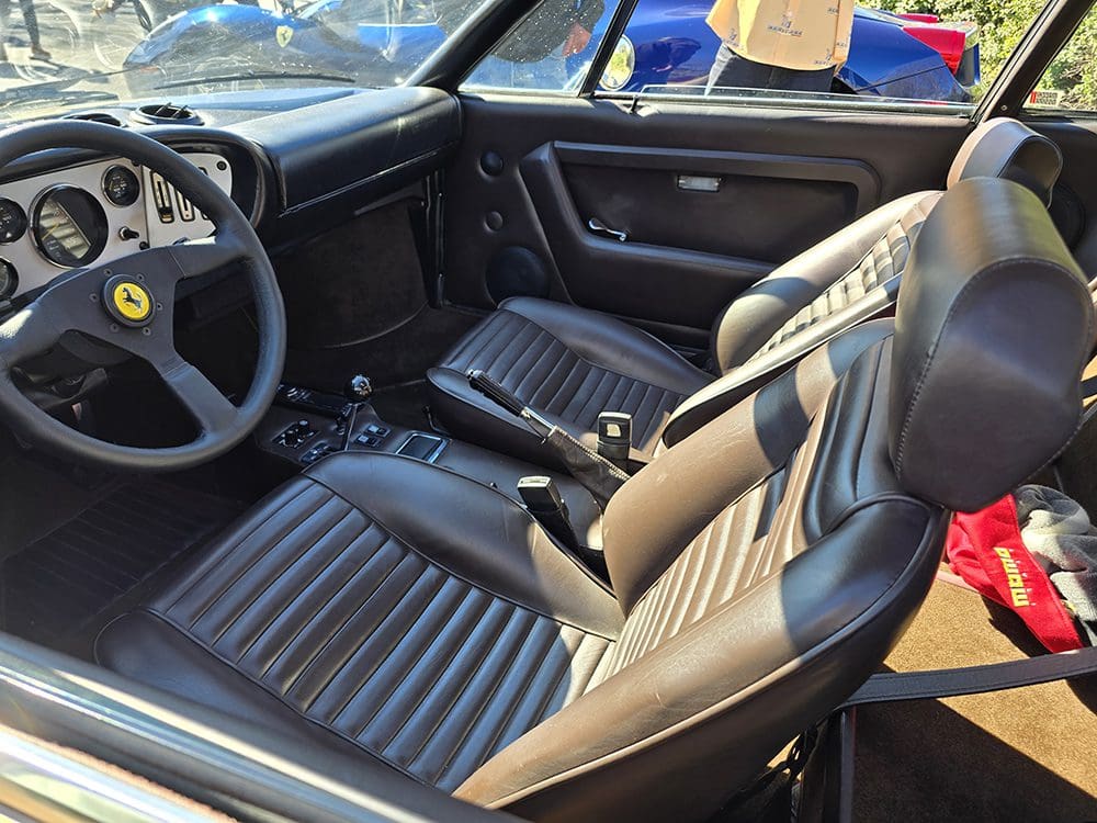 Interior of a vintage car with black leather seats and a classic steering wheel.