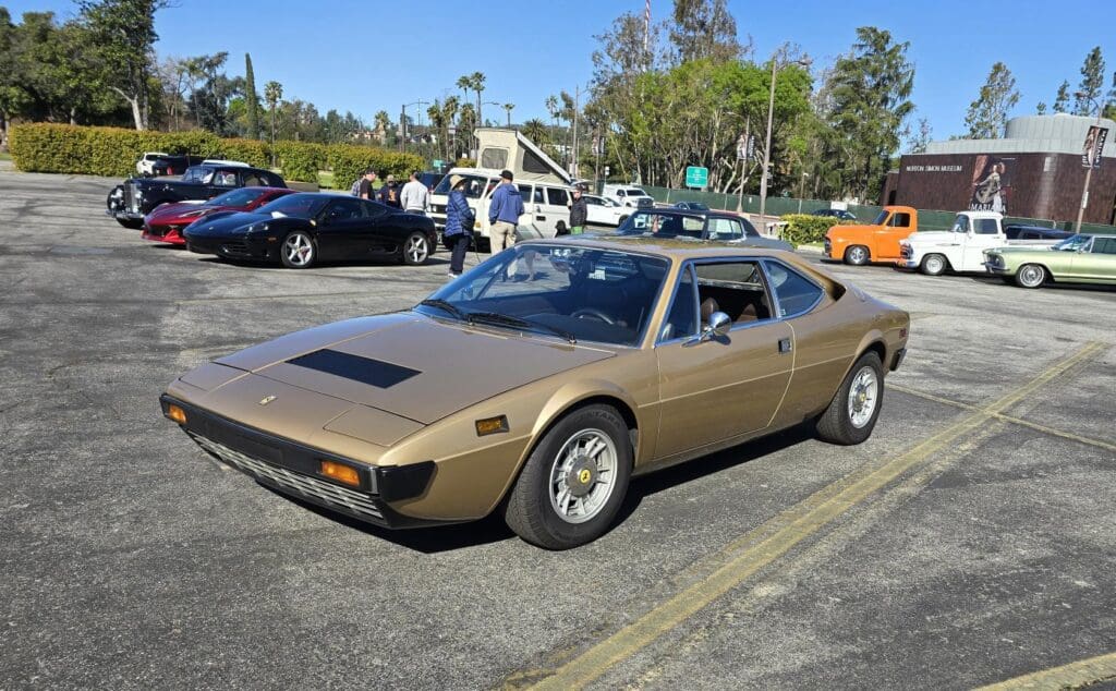 Classic gold sports car parked in a lot on a sunny day.