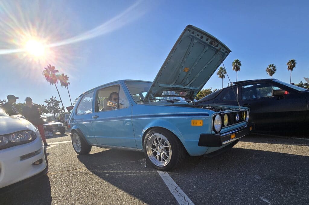 Classic blue car with its hood open under bright sunlight.
