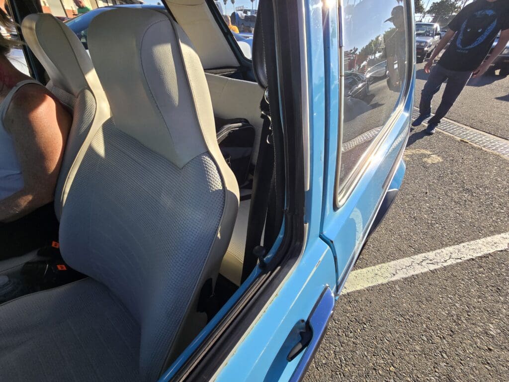Open car door showing blue exterior and gray seat.