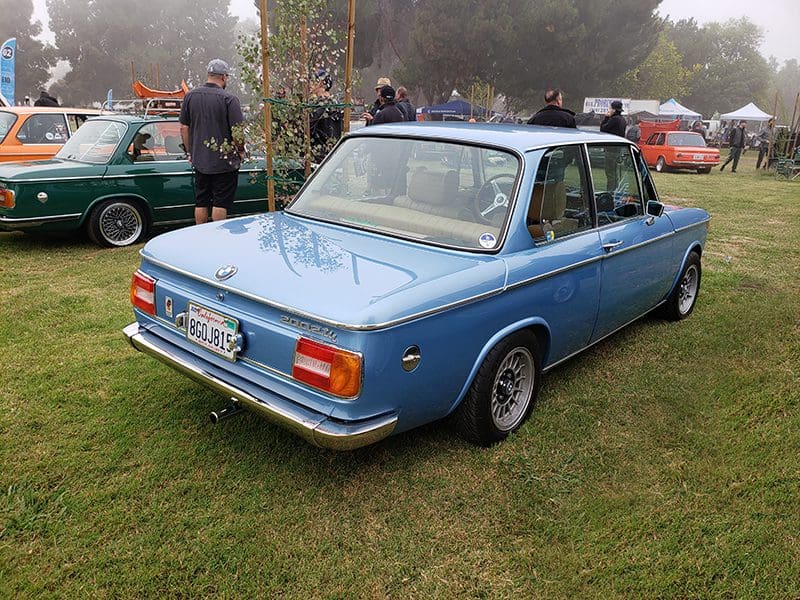 Classic blue BMW 2002 parked on grass at a car show.