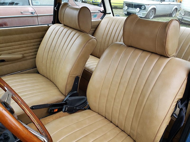 Interior of a vintage car with tan leather seats and headrests.