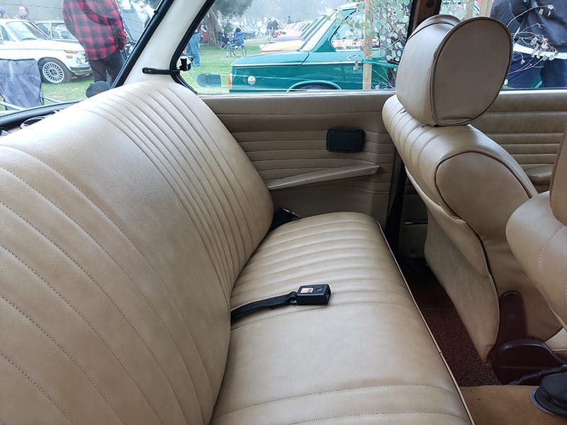 Interior view of a car with beige leather seats and a seatbelt.