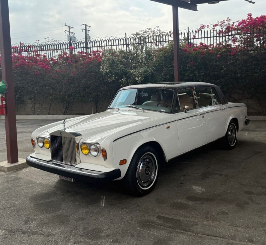 Classic white Rolls-Royce parked outdoors under a canopy.