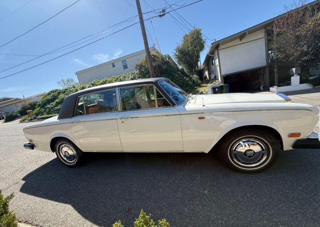 Classic white Rolls-Royce parked outdoors under a canopy.