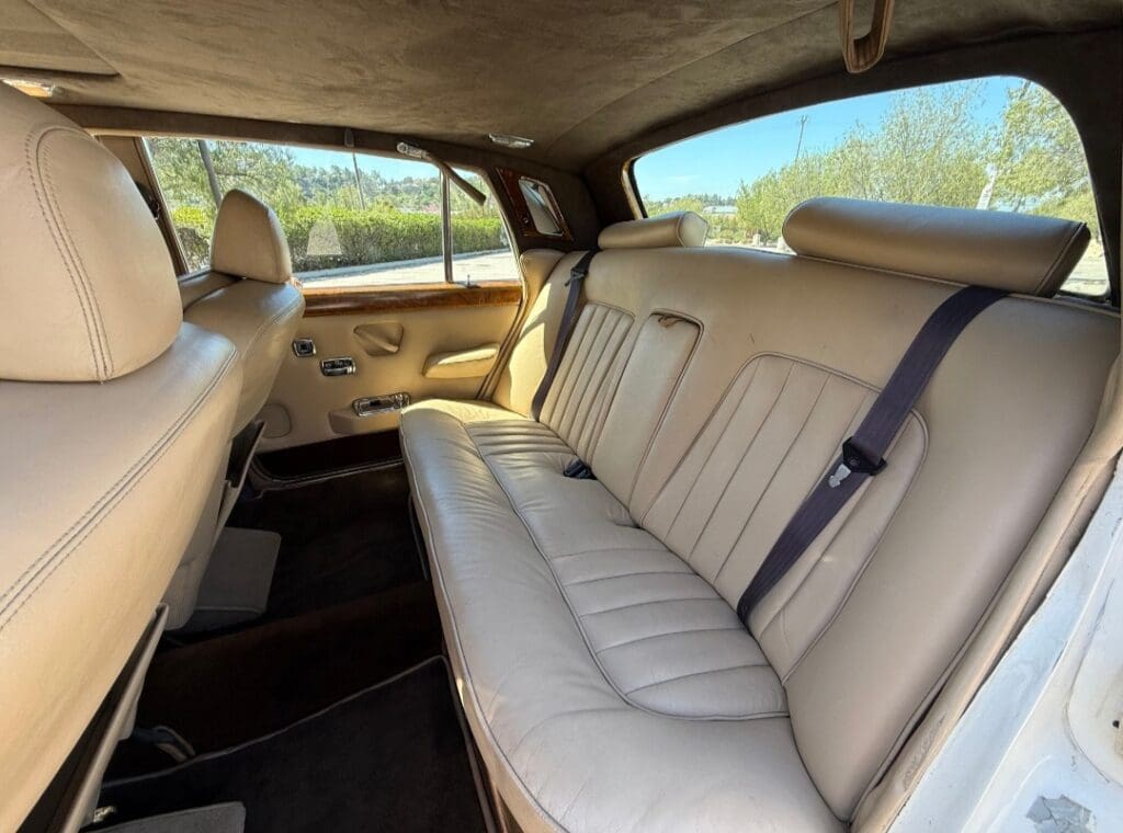Classic white Rolls-Royce parked outdoors under a canopy.