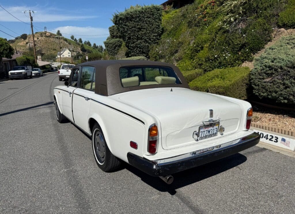 Classic white Rolls-Royce convertible parked on a sunny street.