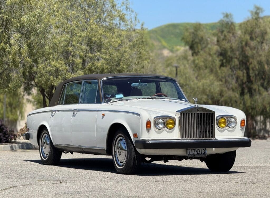 Classic white luxury car parked on a sunny road.
