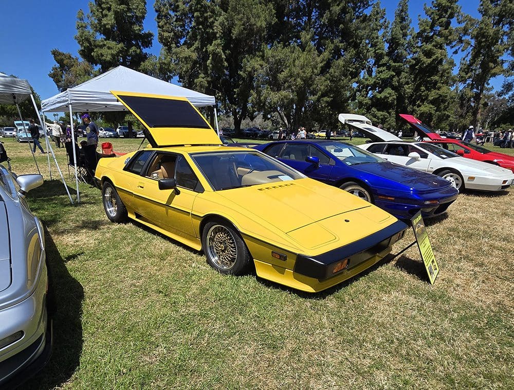 Yellow vintage sports car displayed at outdoor car show.
