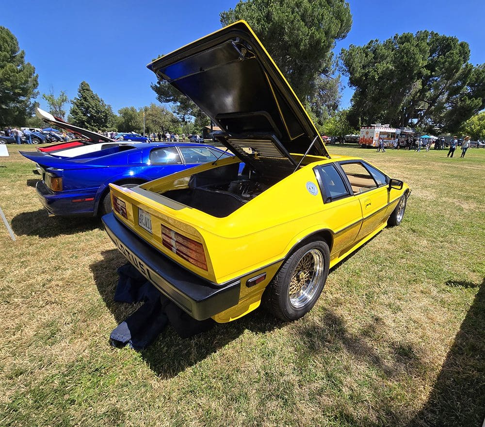 Yellow vintage sports car displayed at outdoor car show.