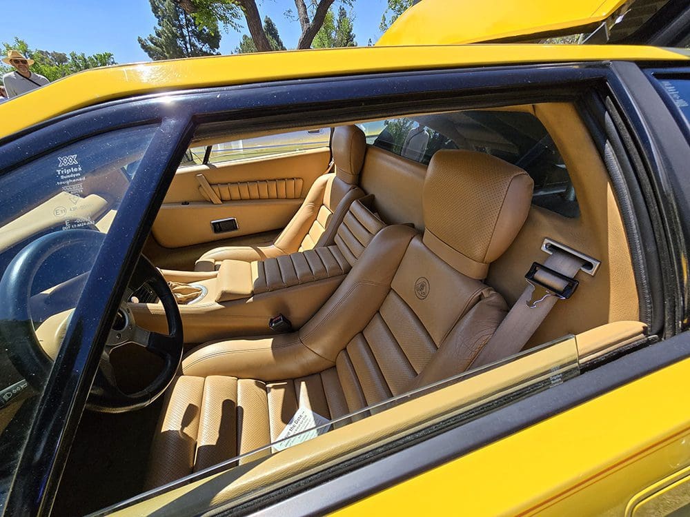 Interior view of a vintage yellow car with tan leather seats.
