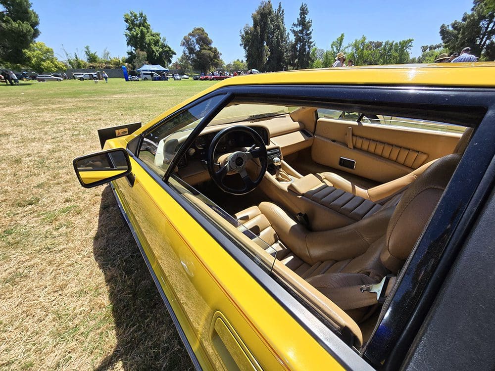 Yellow sports car parked on grass under clear sky.