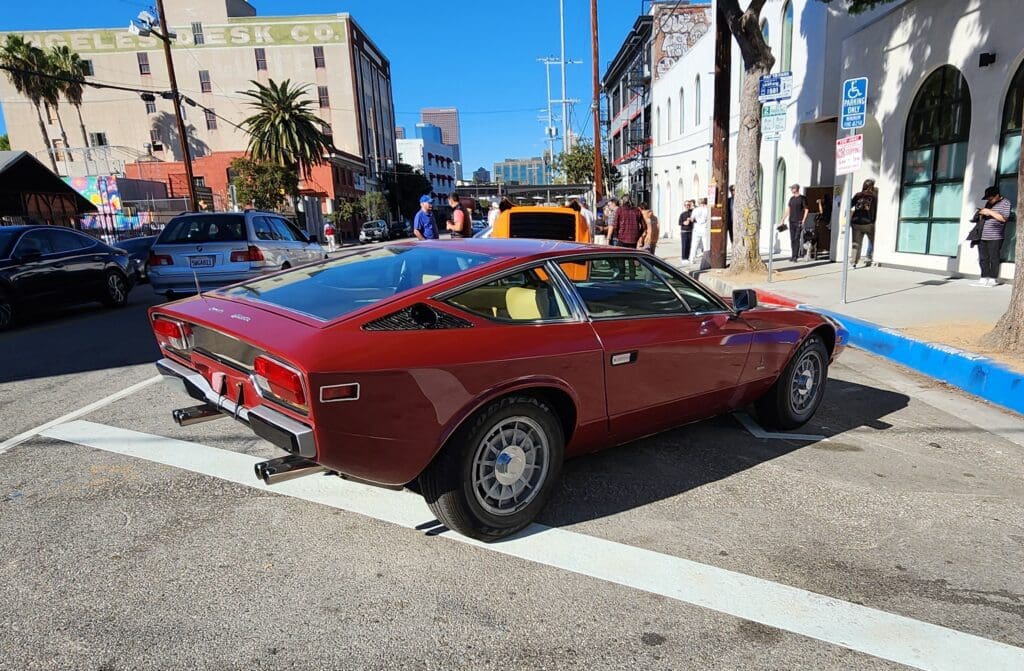 A classic red sports car parked on a sunny city street.