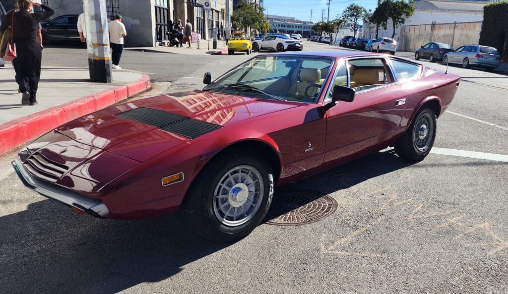 Classic red sports car parked on a sunny city street.