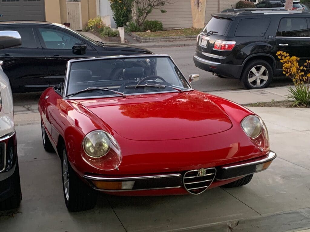 Classic red convertible car parked in driveway.