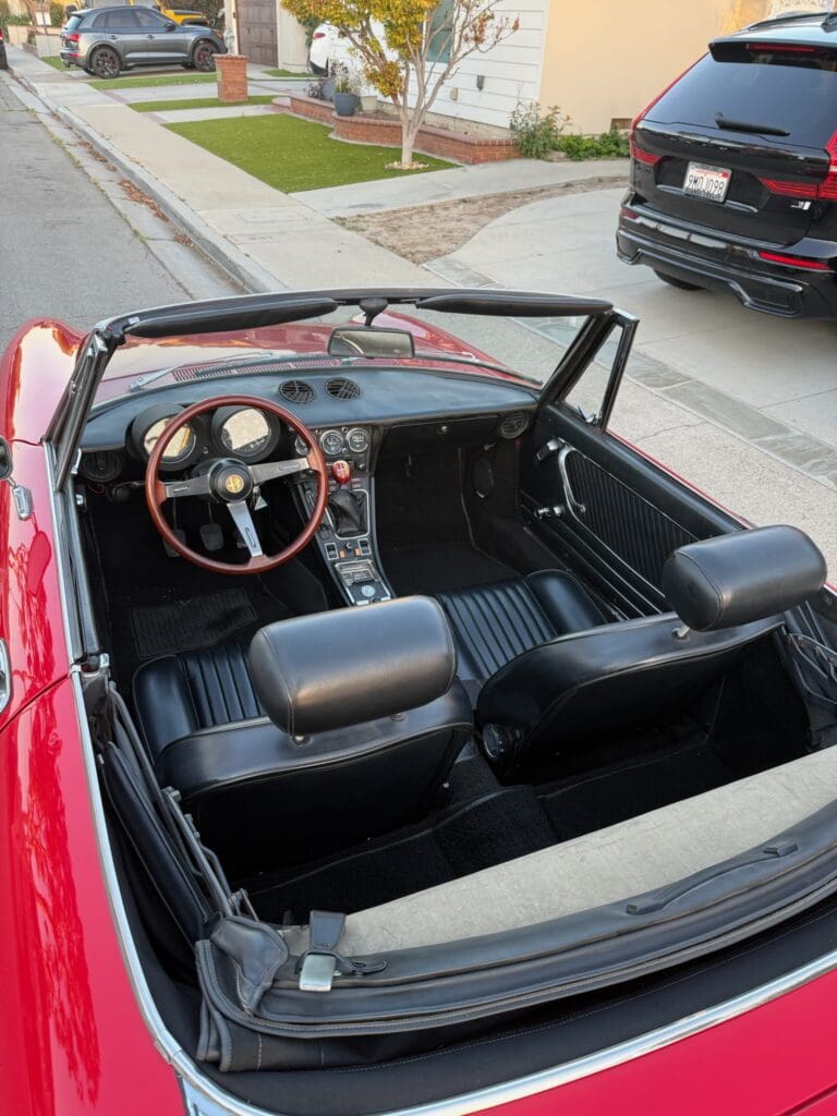 Interior view of a classic red convertible car with black leather seats.