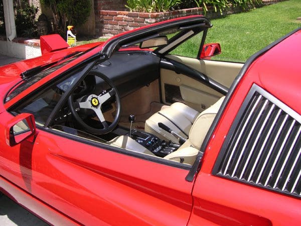 Interior view of a red convertible sports car with beige seats.