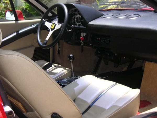 Interior of a classic car with a manual gear shift and steering wheel.