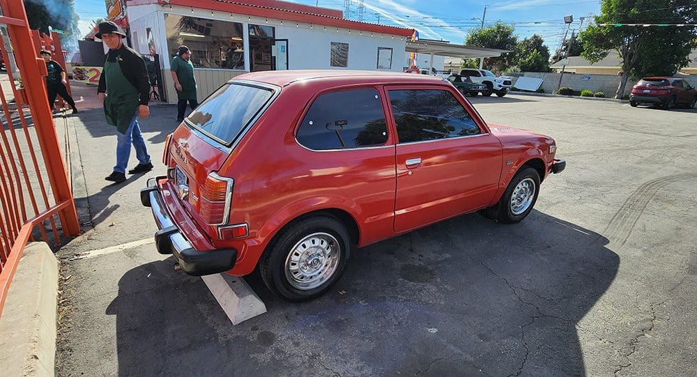 Red vintage compact car parked outdoors near a building.