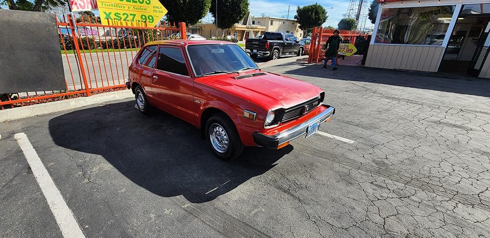 Red vintage hatchback car parked on a sunny street.
