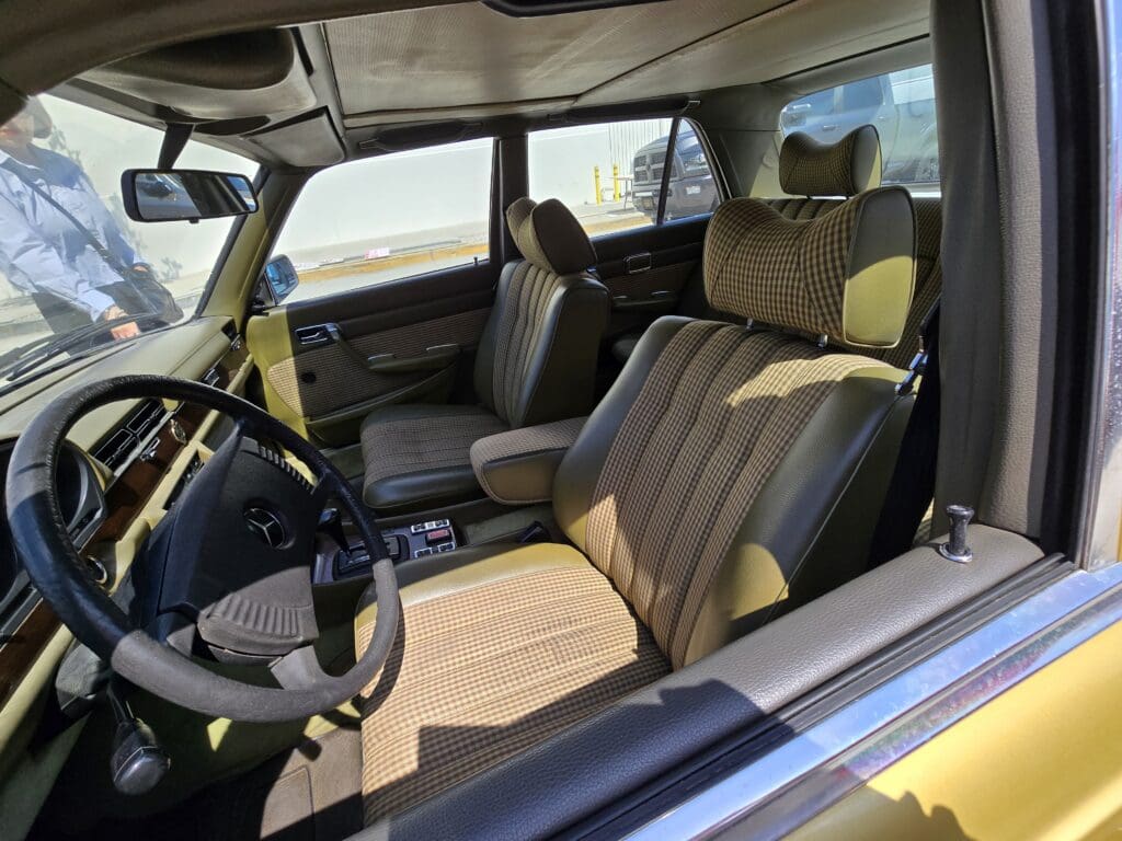 Interior of a vintage car with brown seats and a steering wheel.