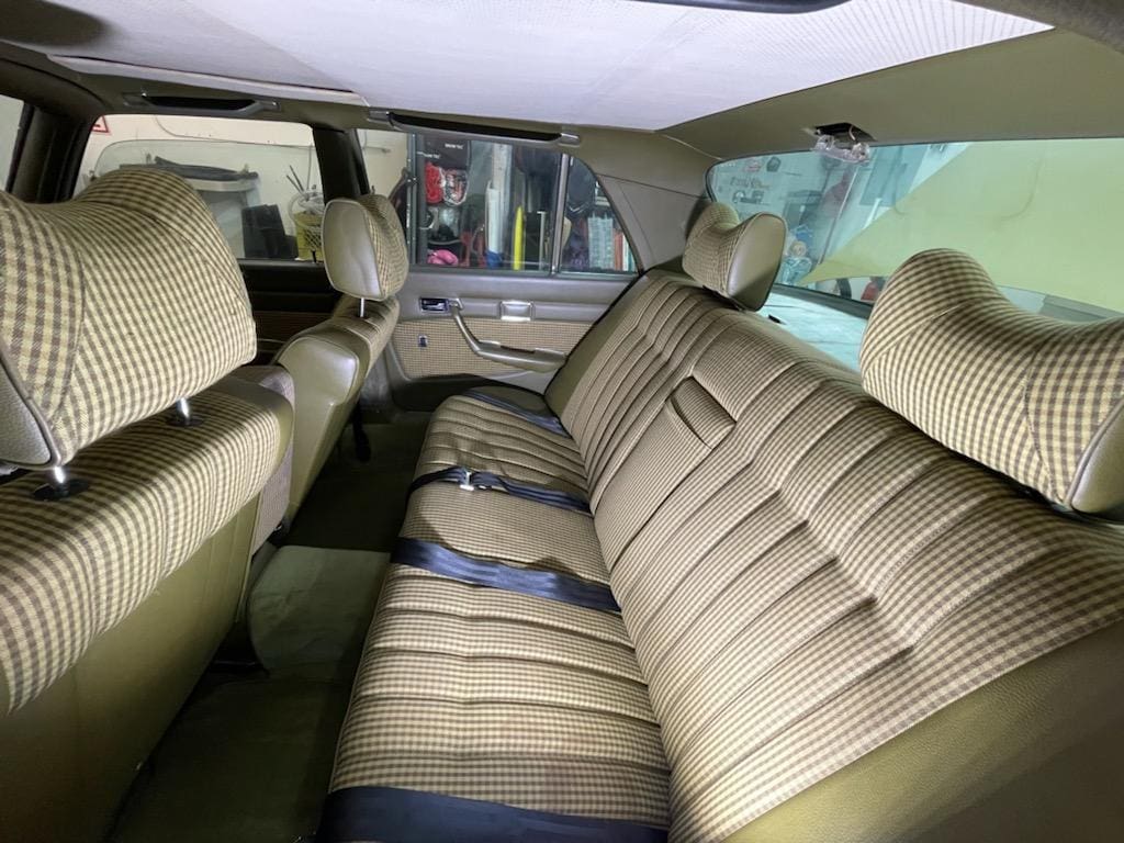 Interior of a vintage car with striped upholstery and spacious backseat.