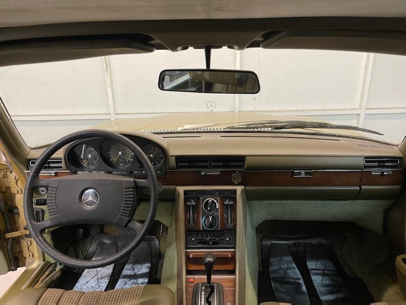 Interior of a vintage car with wooden dashboard and classic steering wheel.
