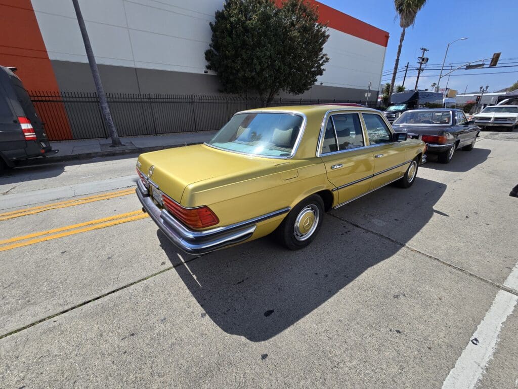Classic yellow vintage car parked on a sunny street.