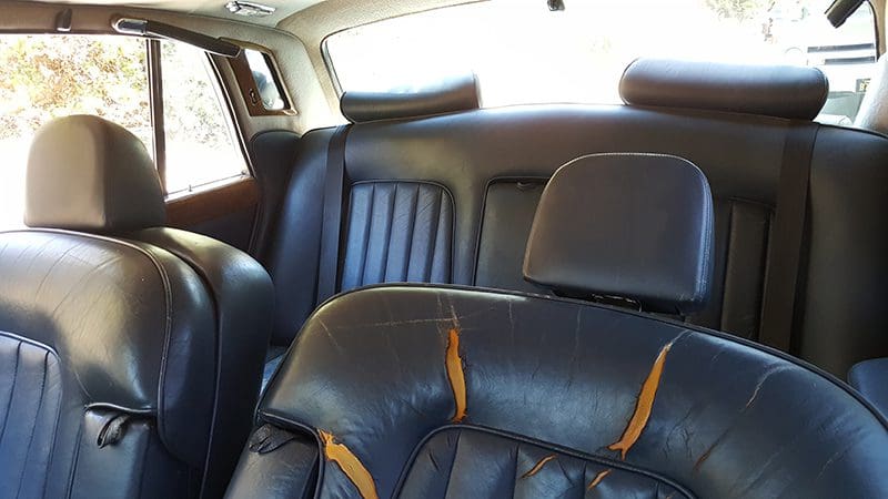 Worn black leather car seats with visible cracks and peeling.