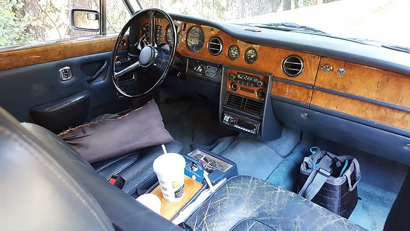 Vintage car interior with wooden dashboard and blue carpeting.