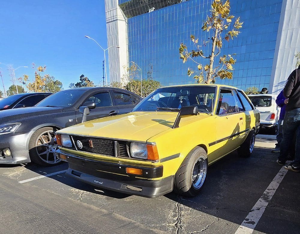 Classic yellow vintage car parked in a sunny lot.