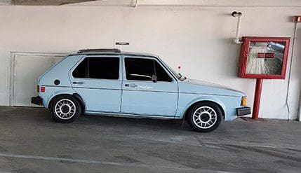 Light blue vintage car parked indoors against a plain wall.