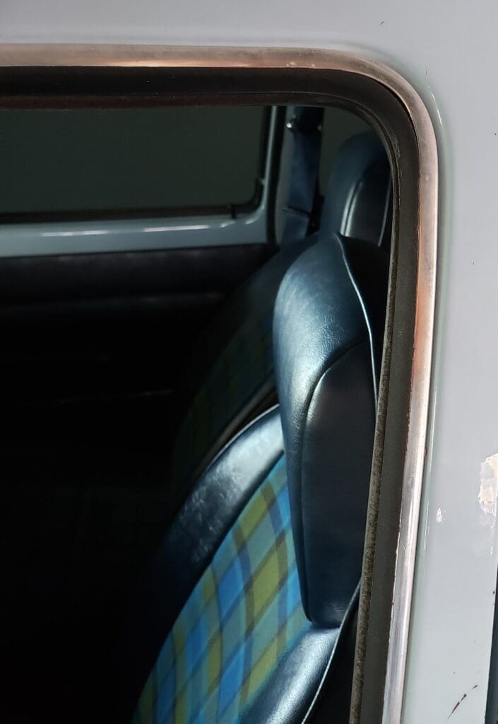 Close-up of a vintage car's interior showing a plaid seat and window.