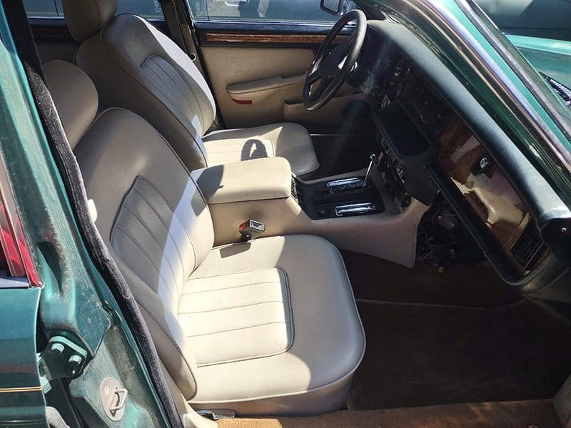 Interior of a car showcasing beige leather seats and a classic dashboard.
