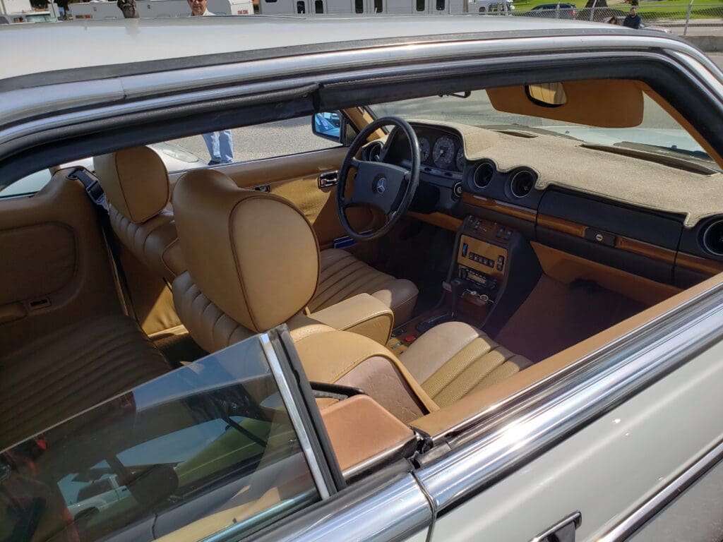 Interior view of a classic car with tan leather seats and vintage dashboard.