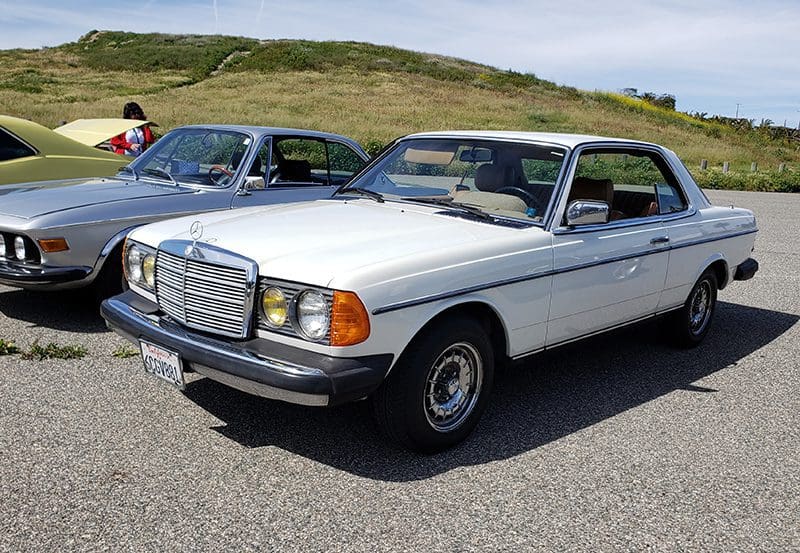 White vintage Mercedes-Benz coupe parked on pavement.