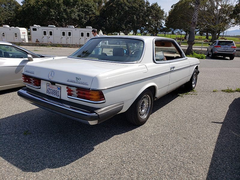 White vintage Mercedes-Benz coupe parked on pavement.