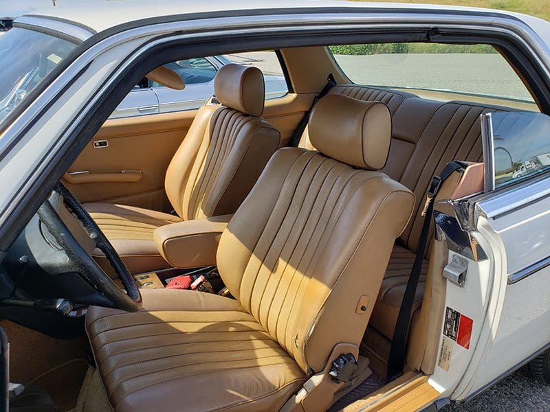 Classic car interior with tan leather bucket seats and detailed stitching.